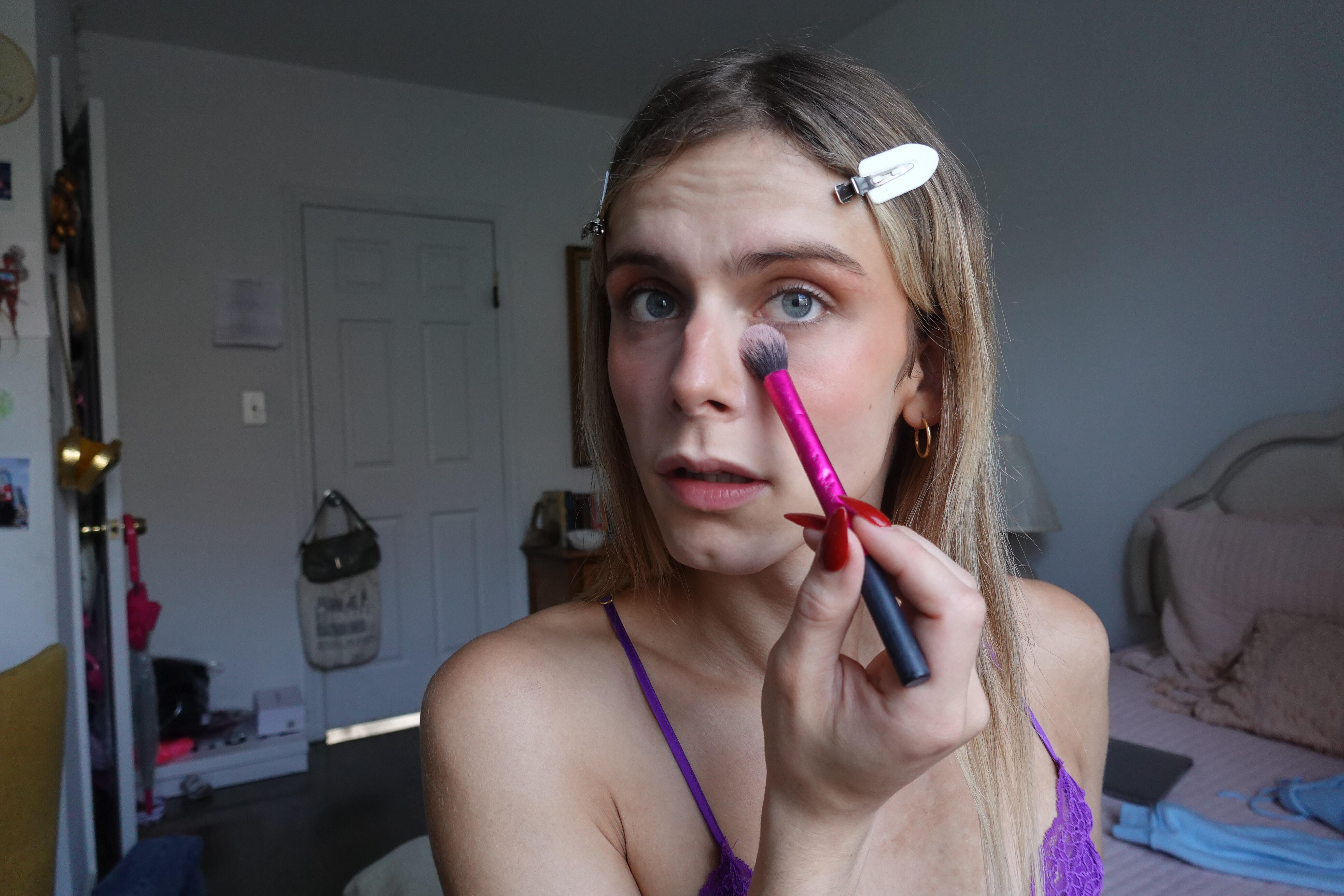 blonde trans woman using makeup brush